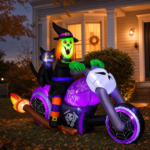 Halloween witch-on-motorcycle inflatable displayed in a front yard at dusk