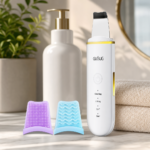 Facial skin scrubber placed beside cleanser and a folded towel on a clean vanity